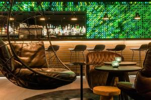 a room with chairs and a bar with a green wall at Motel One Freiburg in Freiburg im Breisgau +23 photos