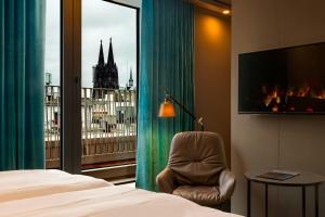 a room with a bed and a window with a fireplace at Motel One Köln-Neumarkt in Cologne
