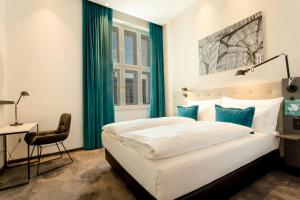 a bedroom with a large white bed and a chair at Motel One Linz-Hauptplatz in Linz