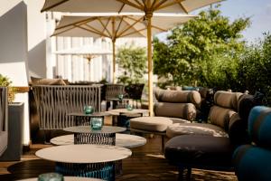 a patio with tables and couches and an umbrella at Motel One Köln-Altstadt in Cologne