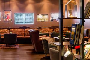 a waiting room with a couch and tables and chairs at Motel One Freiburg in Freiburg im Breisgau