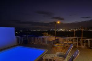 a balcony with a pool and chairs at night at Appartements Des Roses in Le Lamentin