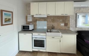 a kitchen with white cabinets and a sink and a microwave at Studio Tout Confort in Fondettes