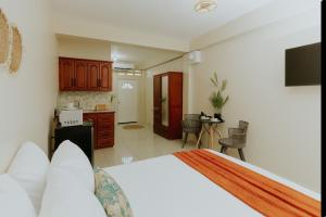 a bedroom with a large bed and a kitchen at Bali-Inspired Studio Mins from Airport in Arima