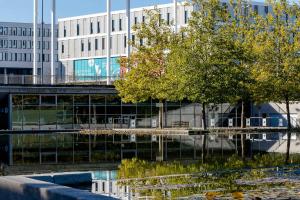 a reflection of trees in the water in front of a building at Motel One München-Messe in Munich