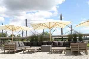 a seating area with umbrellas and couches and tables at Motel One München-Garching in Garching bei München