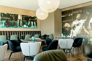 a waiting room with tables and chairs and a large picture at Motel One München-Garching in Garching bei München +23 photos