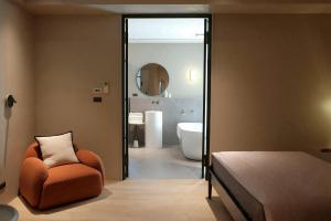 a bedroom with an orange chair and a bathroom at Chuan Inn圈旅 站前館 in Tainan +56 photos