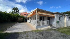 a small white house with a porch and a driveway at P'tii repos Soleil in Sainte-Anne