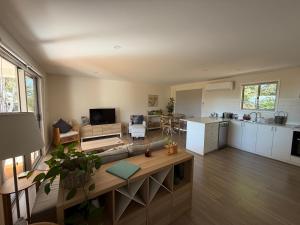 a kitchen and living room with a couch and a table at Grevillea Cottage in Murrumbateman