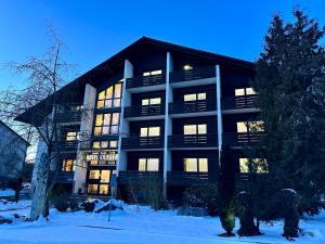 un grande edificio con le luci accese nella neve di Hotel Krieger Regensburg a Pettendorf