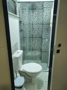a bathroom with a toilet and a glass shower at Kitnet no Centro Garagem, ar e Wi-Fi in Itaperuna +9 photos