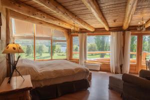 a bedroom with a bed in a room with windows at Estancia Peuma Hue in San Carlos de Bariloche