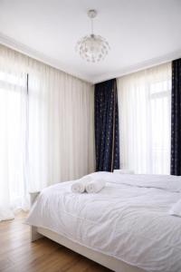 a bedroom with a bed with white sheets and a chandelier at Chill House in Kutaisi