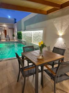 a dining room with a table and chairs and a swimming pool at Casa Don Magalhães in Barra de São Miguel