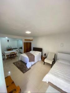 a bedroom with two beds and a table and a desk at Hospedaria Klagemberg in Treze Tílias