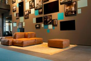 a living room with two brown leather couches and pictures on the wall at Motel One München-Campus in Munich