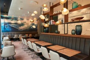 a restaurant with wooden tables and white chairs at Motel One Zürich in Zurich