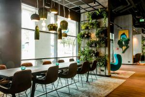 a table and chairs in a room with plants at Motel One München-East Side in Munich +17 photos