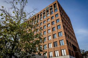 a tall brick building with a tree in front of it at Motel One Wiesbaden in Wiesbaden