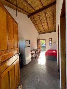 a kitchen with a refrigerator and a bedroom with a table at Casa Mojubá in Porto Seguro