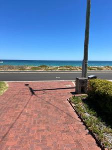 a shadow of a pole on a brick sidewalk near the ocean at Beach House Studio in Busselton