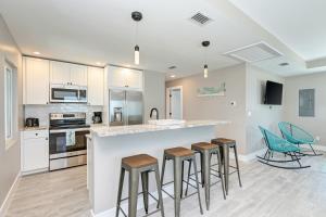 a kitchen with white cabinets and bar stools at Ami Gulf Lookout-Views Of The Gulf From Every Room-Rooftop Terrace in Bradenton Beach +31 photos
