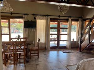 a dining room with a table and some windows at Cabañas El Alemán in Cerrillos