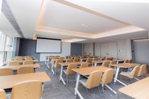 an empty classroom with tables and chairs and a screen at JI Hotel Suzhou Wujiang Development Zone in Suzhou