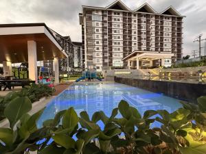 a hotel pool with a large building in the background at The Infinity View in Talisay