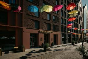 a group of colorful umbrellas hanging from a building at The Cloud One Gdansk in Gdańsk