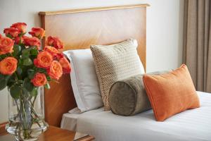 eine Vase mit Blumen auf einem Bett in der Unterkunft Lancaster Gate Hotel in London