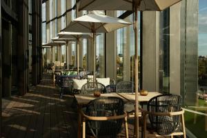 an outdoor patio with tables and chairs and umbrellas at The Cloud One Düsseldorf-KöBogen in Düsseldorf