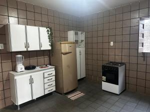 a kitchen with white cabinets and a refrigerator at 3R acomodações in Juazeiro do Norte