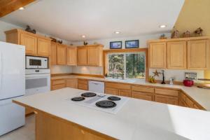 a kitchen with wooden cabinets and a white stove top oven at Pine Tree Cottage by NW Comfy Cabins in Leavenworth