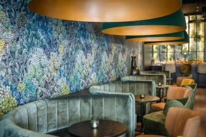 a restaurant with couches and tables and a floral wall at Motel One München-Hauptbahnhof in Munich +49 photos