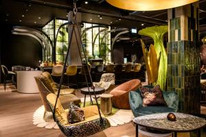 a lobby with chairs and tables and a bar at Motel One München-Hauptbahnhof in Munich