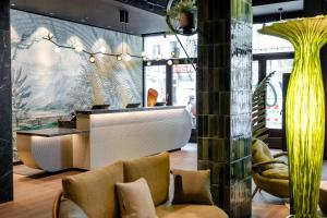 a lobby with a table and chairs in a building at Motel One München-Hauptbahnhof in Munich
