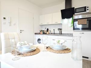 a white kitchen with two plates and wine glasses on a counter at Elroi Suite in Minden