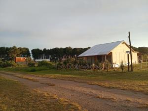 a barn and a dirt road next to a field at Cabaña in Necochea