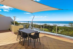 a table and chairs on a balcony with a view of the ocean at Santorini Twin Waters in Mudjimba