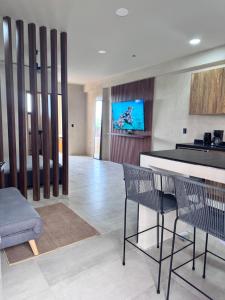 a kitchen with chairs and a counter with a tv on the wall at Xiib Kaab Estudio con Jacuzzi in Tulum
