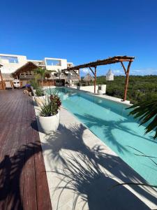 a large swimming pool with a wooden deck with plants at Xiib Kaab Estudio con Jacuzzi in Tulum