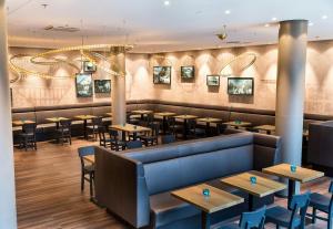 a restaurant with tables and chairs in a room at Motel One Wien-Hauptbahnhof in Vienna