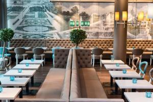 a restaurant with tables and chairs and a mural at Motel One Wien-Hauptbahnhof in Vienna +28 photos