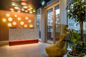 a lobby with a yellow bench and a window at Motel One Rotterdam in Rotterdam