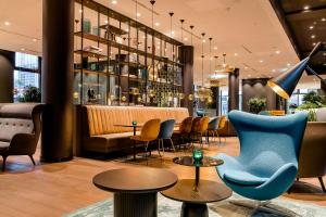 a lobby with chairs and a bar in a building at Motel One Köln-Messe in Cologne