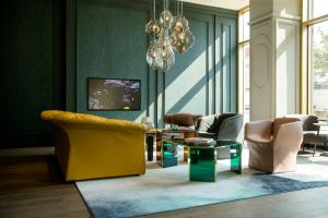 a living room with chairs and a table and a chandelier at Motel One Graz in Graz