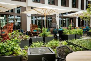 an outdoor garden with tables and chairs and umbrellas at Motel One Köln-Messe in Cologne