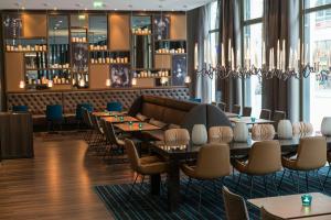 a restaurant with tables and chairs and windows at Motel One Leipzig-Nikolaikirche in Leipzig